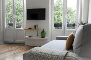 een woonkamer met een bank, een tv en ramen bij Zelije Apartments Trindade in Porto