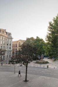 a man walking past a tree on a street at Zelije Apartments Trindade in Porto