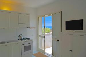 a kitchen with white cabinets and a television and a window at Villa Alba in Acitrezza