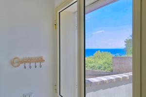 a sliding glass door with a view of the ocean at Villa Alba in Acitrezza