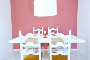 a white table and chairs in a room with a pink wall at Villa Alba in Acitrezza