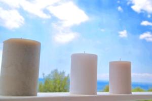 three white candles sitting on a window sill at Villa Alba in Acitrezza