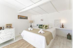 a white bedroom with a bed and a dresser at O Moinho da Roca in Azoia