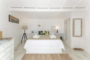 a white bedroom with a large bed and a mirror at O Moinho da Roca in Azoia