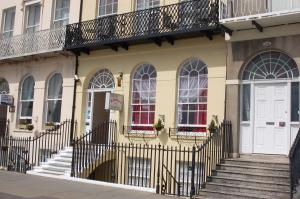 a yellow building with stairs and a white door at The Edenhurst Guesthouse in Weymouth