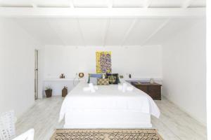 a white bedroom with a white bed and a wooden floor at O Moinho da Roca in Azoia