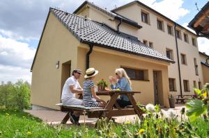 three people sitting at a picnic table in front of a house at Miraka in Lipno nad Vltavou