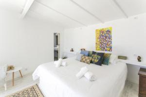 a white bedroom with a white bed with pillows at O Moinho da Roca in Azoia