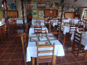 un comedor con mesas blancas y sillas de madera en Pousada do Peralta, en Bonito