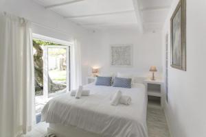 a white bedroom with a white bed and a window at O Moinho da Roca in Azoia
