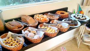 a table with baskets of different types of pastries at Pousada Sol da Trindade in Trindade