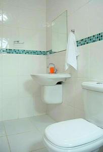 a white bathroom with a toilet and a sink at Pousada Sol da Trindade in Trindade