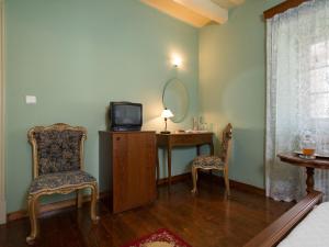 a room with a desk with a tv and two chairs at Villa De Loulia in Peroulades