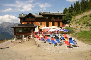 a group of chairs and umbrellas in front of a building at Chalet Dei Rododendri in Valdisotto