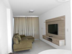 a living room with a couch and a television at Flat Beira Mar in Recife