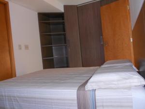 um quarto com uma cama e armários de madeira em Flat Beira Mar em Recife