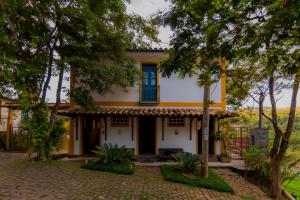 uma casa com uma janela azul e árvores em Pousada do Canto em Rio Acima