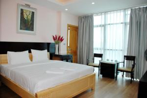 a bedroom with a large white bed and a desk at Nice Hotel in Hanoi