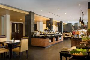 a restaurant with a bar with chairs and tables at Hotel Santika Premiere Malang in Malang