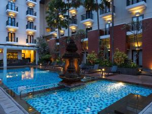 a pool in the courtyard of a hotel with a fountain at Hotel Santika Premiere Malang in Malang