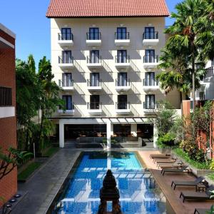 a hotel with a swimming pool in front of a building at Hotel Santika Premiere Malang in Malang