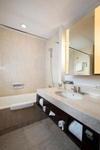 a bathroom with a sink and a tub and a mirror at Hotel Santika Premiere Malang in Malang