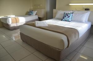 a hotel room with two beds and a couch at Ambassador Motel in Rockhampton