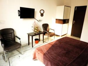 a bedroom with two chairs and a table and a tv at Time Square Guest House in Jalandhar