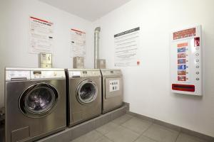 una lavandería con 3 lavadoras y letreros en la pared en Séjours & Affaires Angers Atrium, en Angers