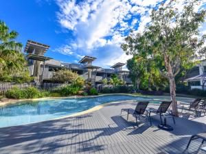 a swimming pool with chairs in front of a house at East On Byron in Byron Bay