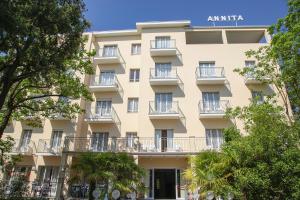 an apartment building with balconies and trees at Hotel Annita Cervia in Cervia