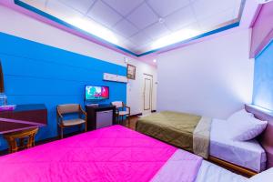 a room with two beds and a desk and a tv at Kending Fengcai Homestay in Kenting