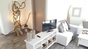 a living room with a white couch and a tv at Akrotiri Villas Skyros in Skiros