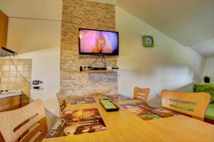 a dining room with a table and a television on a wall at Apartma David Rogla in Zreče