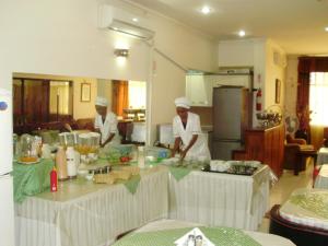 Dois chefs numa cozinha a preparar comida. em Hotel Royal Residencial em Maputo