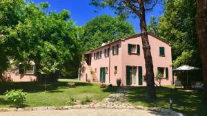 a pink house with a tree in front of it at La Visciola - Country House del Conero in Sirolo