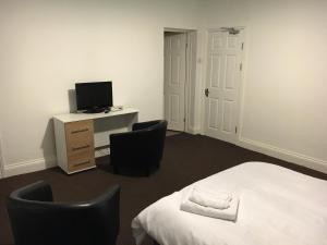 a bedroom with a bed and two chairs and a television at Manor Studio in Walsall