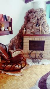a living room with a stone fireplace and a chair at Vila De turist in Nova Varoš