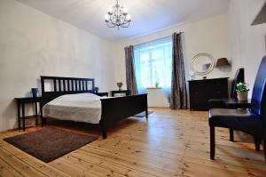 ソポトにあるVictus Apartamenty, Apartament Osloのベッドルーム1室(ベッド1台、椅子、シャンデリア付)