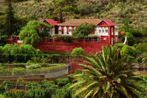 une maison rouge et blanche au milieu d'un jardin dans l'établissement Hotel Rural Las Longueras, à Agaete