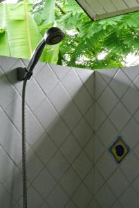 a shower head in a bathroom with white tiles at Jamjuree Garden in Ban Thung Ma Nieo