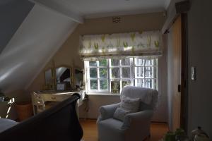 a living room with a chair and a window at Almond Cottage Bed & Breakfast in Somerset West