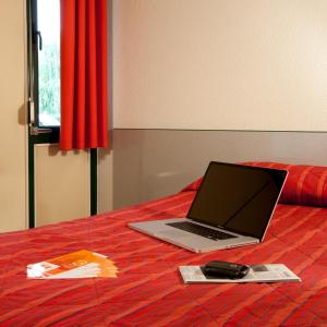 a laptop computer sitting on top of a bed at Premiere Classe Lyon Sud - Chasse Sur Rhône in Chasse-sur-Rhône