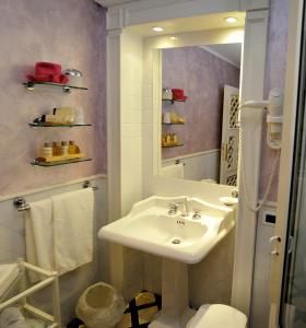 ein weißes Badezimmer mit einem Waschbecken und einem Spiegel in der Unterkunft Hotel Porto Pirgos in Parghelia