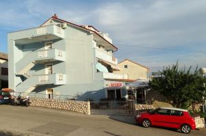 a red car parked in front of a building at Pansion Belveder in Crikvenica