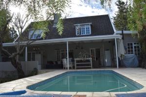 a house with a swimming pool in front of a house at Almond Cottage Bed & Breakfast in Somerset West
