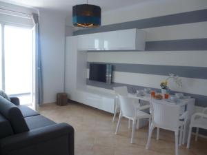 ein Wohnzimmer mit einem Tisch und weißen Stühlen in der Unterkunft Beautifull Holiday Apartment Larisa in Sarandë