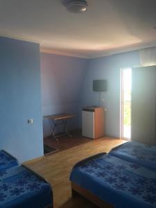 Cette chambre comprend 2 lits, une table et une fenêtre. dans l'établissement Kvariati - Guest House, à Kvariati