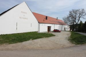a white barn with a red roof and a car parked next to it at Penzion Vanůvecký Dvůr in Telč