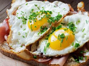 a sandwich with eggs and ham on a plate at Hotel Elegance in New Delhi